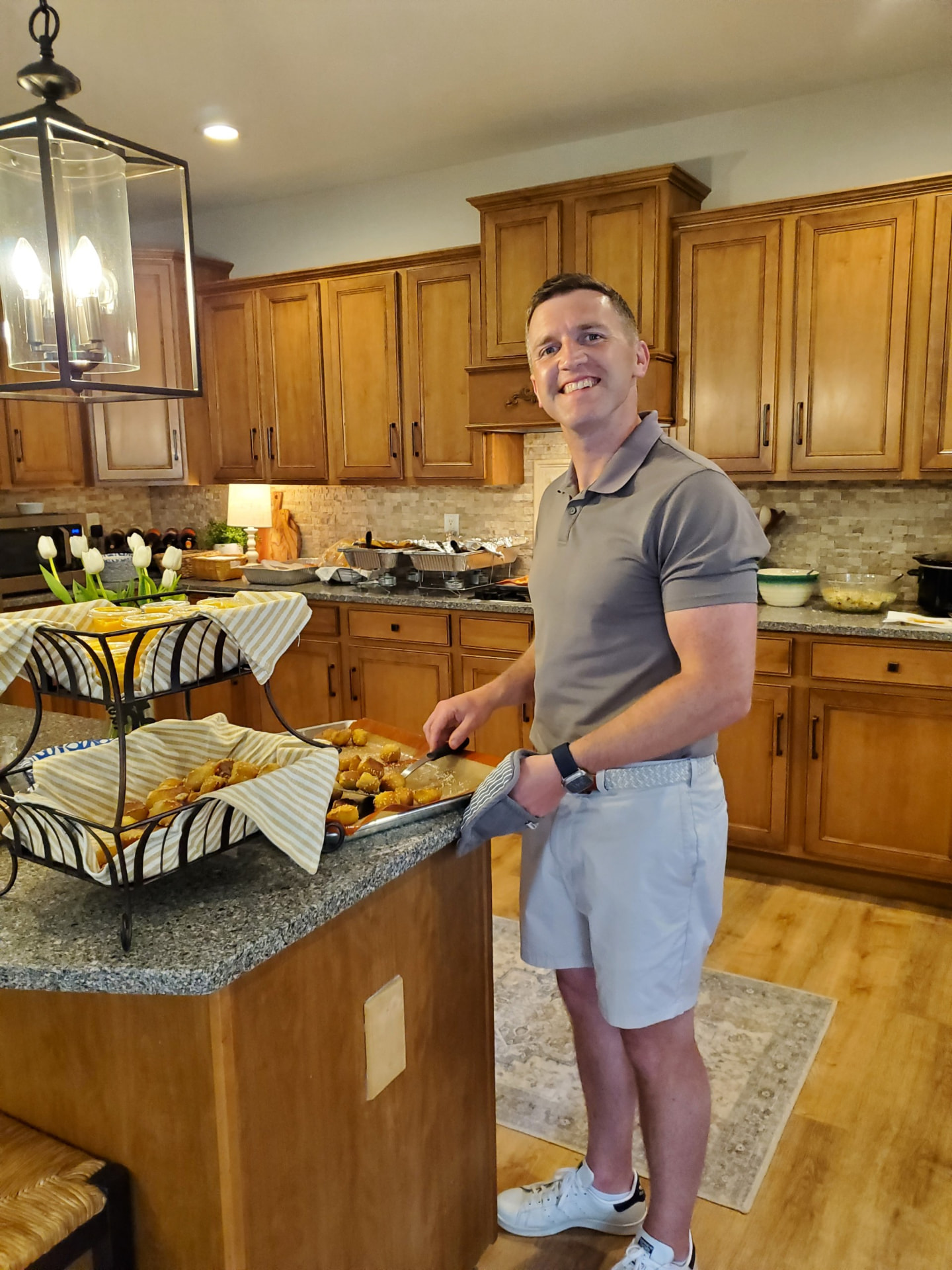 Nate, the baker behind The Pretzel Post, holding a baking sheet and oven mitt in his kitchen